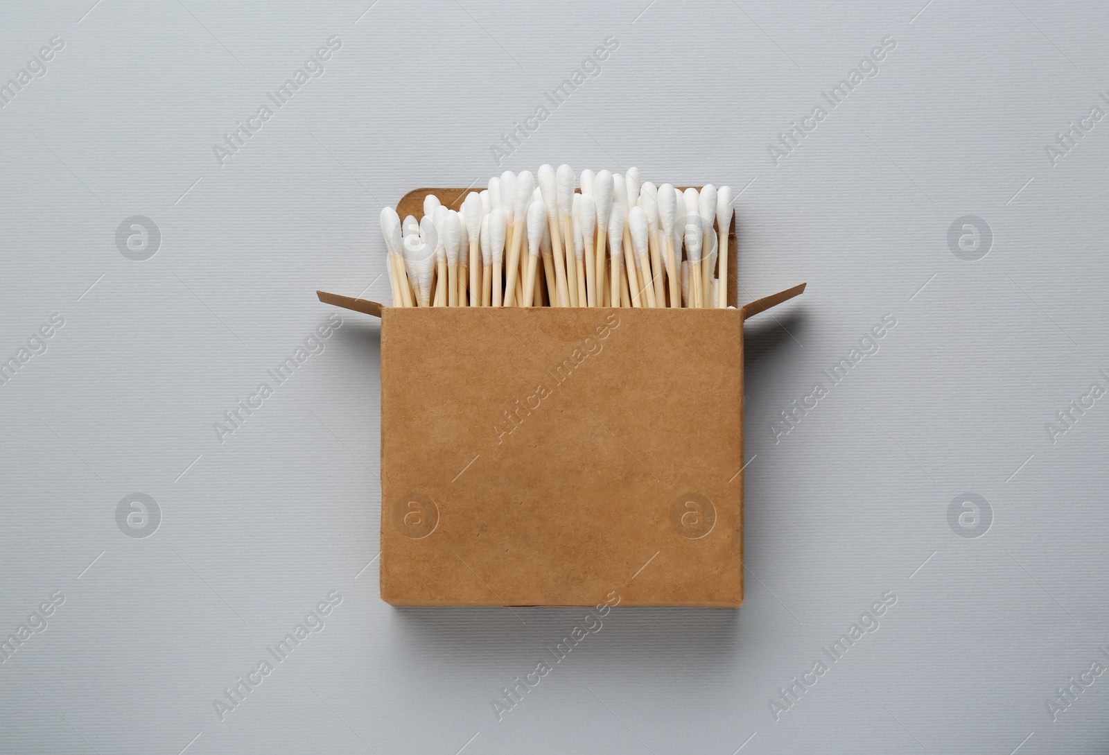 Photo of Cardboard box with cotton buds on light grey background, top view