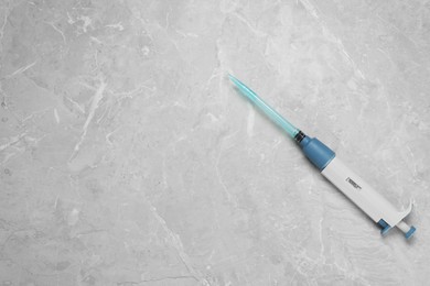 Photo of Laboratory analysis. Micropipette with liquid on grey marble table, top view. Space for text