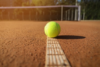 Bright yellow tennis ball on clay court