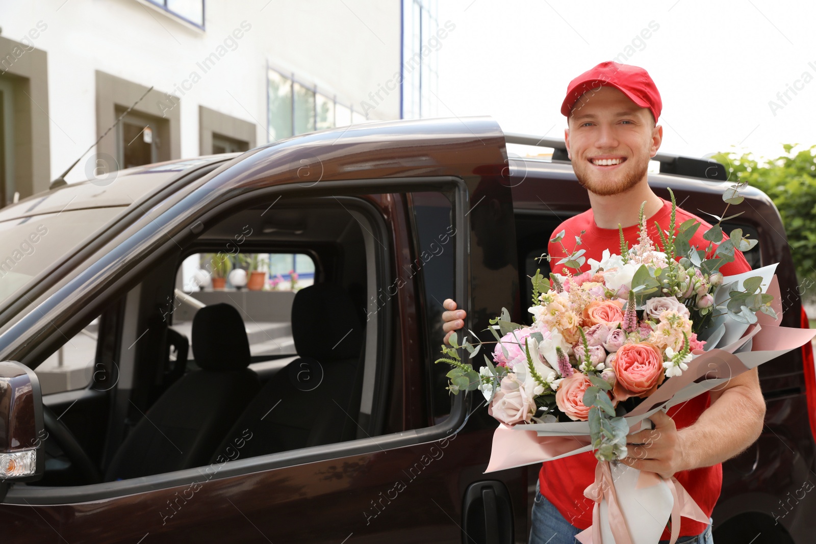 Photo of Delivery man with beautiful flower bouquet near car outdoors