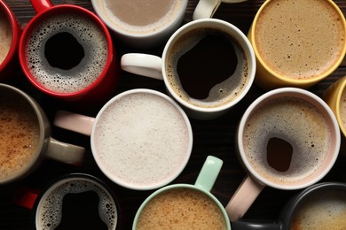 Photo of Many different cups with aromatic coffee on wooden table, flat lay