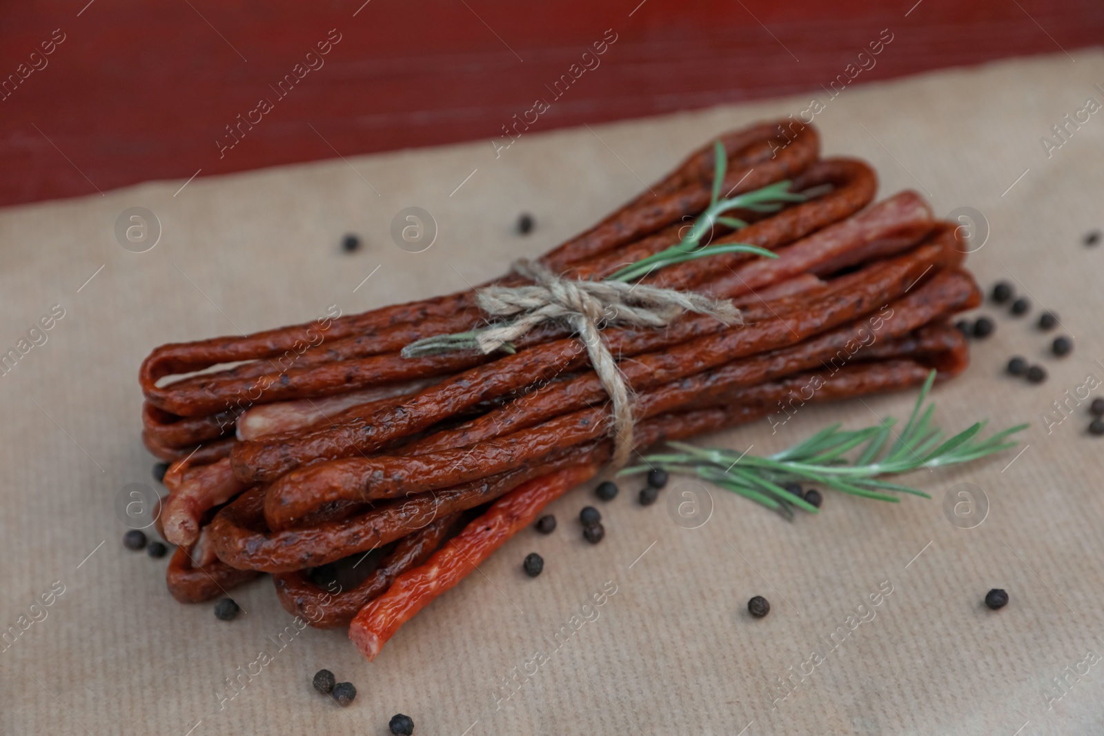 Photo of Tasty dry cured sausages (kabanosy) and spices on parchment paper