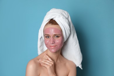 Photo of Young woman with pomegranate face mask on light blue background