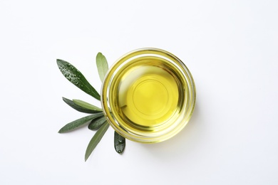 Photo of Little bowl with fresh olive oil and leaves on white background