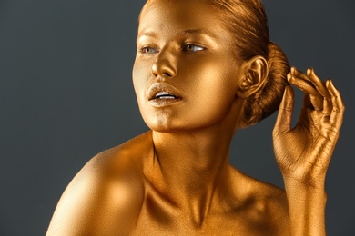 Photo of Beautiful young woman with golden paint on her body against color background