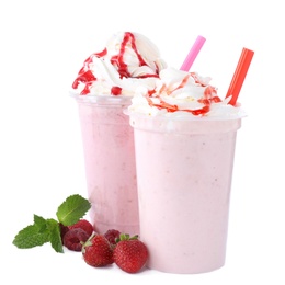 Photo of Tasty fresh milk shakes in plastic cups with ingredients on white background