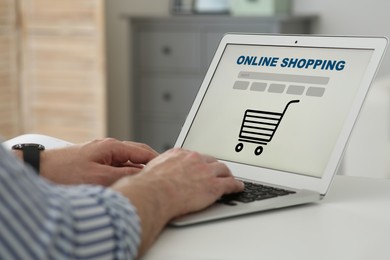 Image of Man using laptop for online shopping at white table, closeup