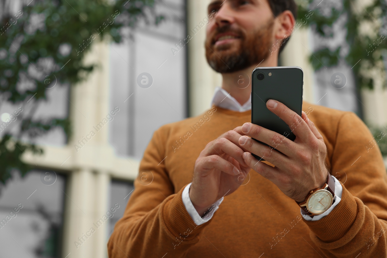 Photo of Handsome man with smartphone on city street, closeup. Space for text