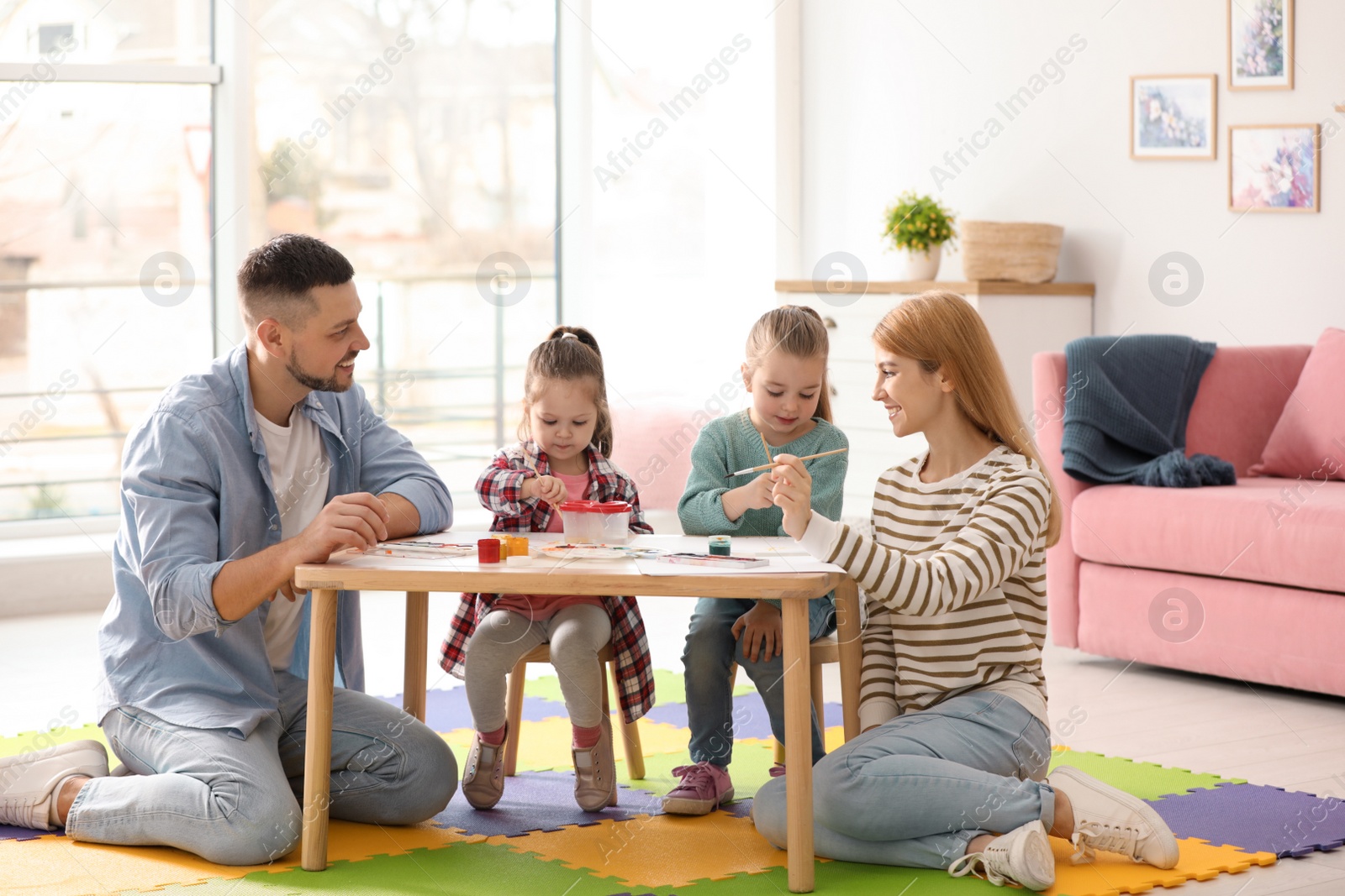 Photo of Lovely family painting at table indoors. Playing with children