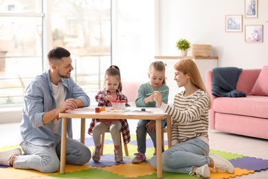 Photo of Lovely family painting at table indoors. Playing with children