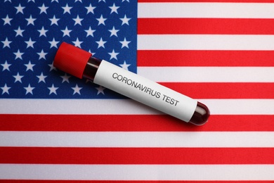 Test tube with blood sample on American flag, top view. Coronavirus pandemic in USA