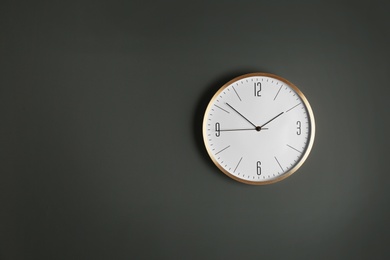 Stylish analog clock hanging on gray wall, space for text. Time of day