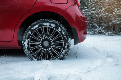 Photo of Modern car on snowy road in winter forest, closeup. Space for text