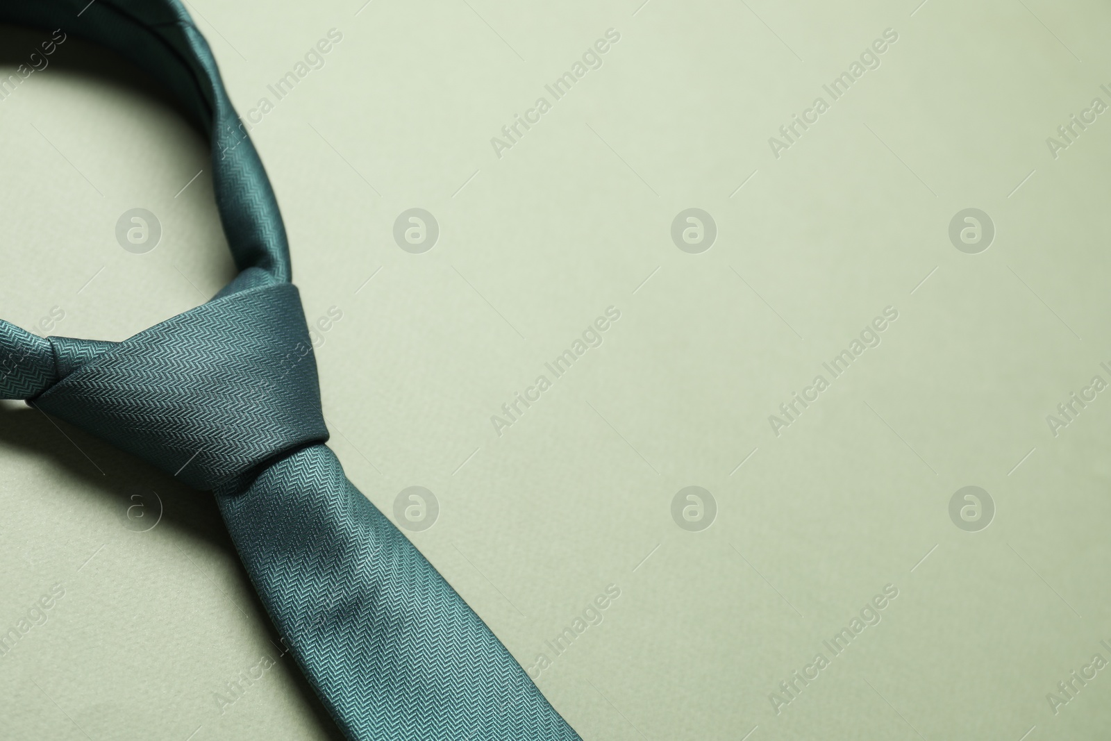 Photo of Stylish necktie on light green background, closeup. Space for text