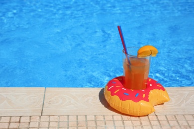 Photo of Tasty refreshing cocktail on edge of swimming pool