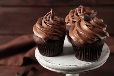 Photo of Delicious cupcakes decorated with cream on white wooden stand, closeup