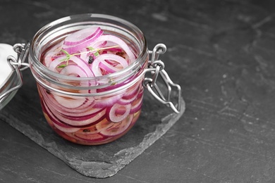 Jar of pickled onions on grey table. Space for text