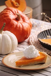 Photo of Piece of fresh homemade pumpkin pie with whipped cream on table