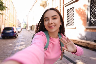 Beautiful young travel blogger streaming on city street