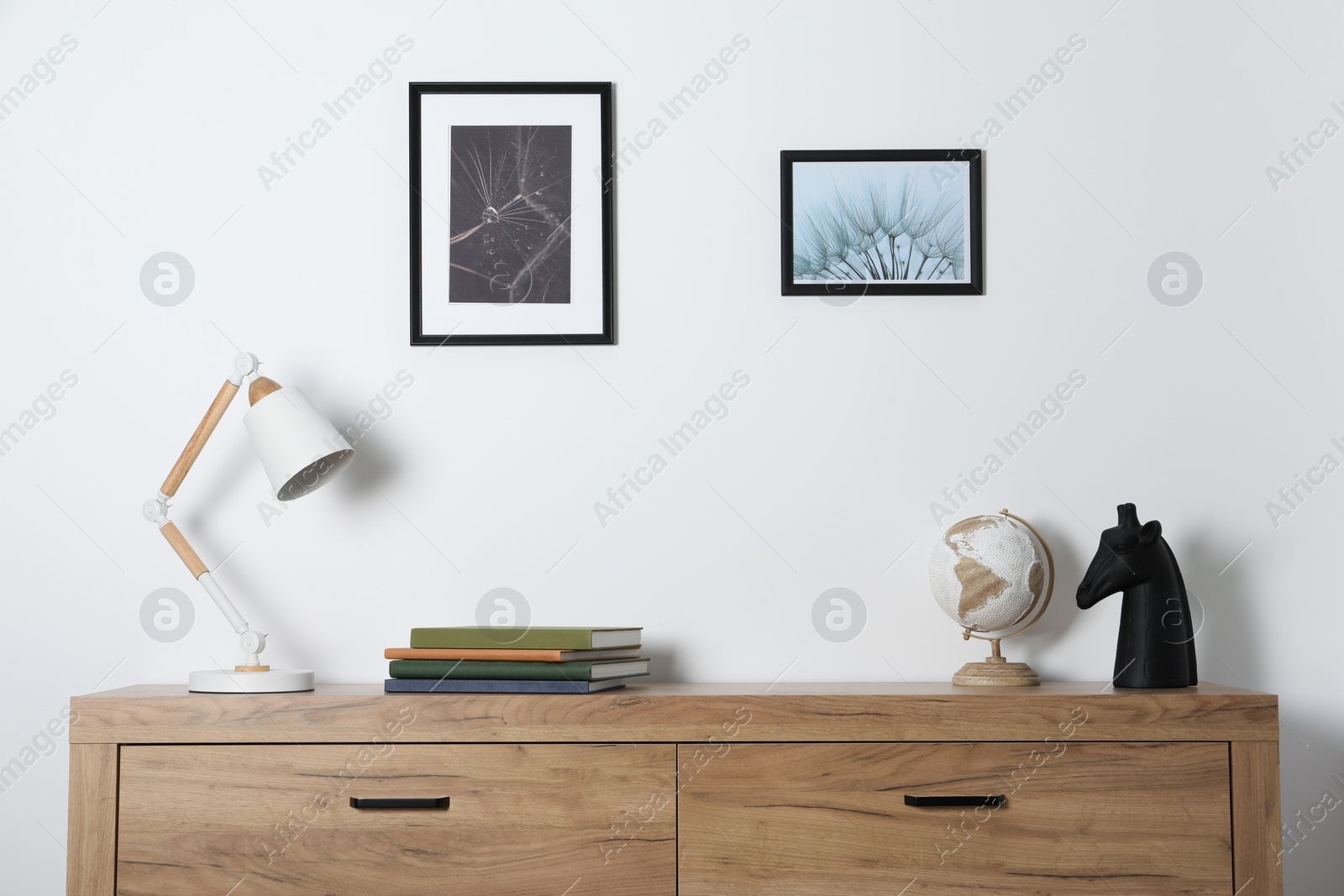 Photo of Desk lamp, books and decor on wooden chest of drawers indoors