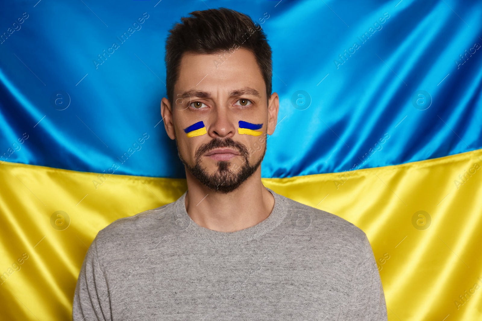 Photo of Man with face paint near Ukrainian flag