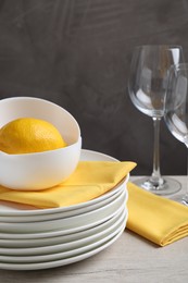 Set of clean dishware and lemon on light wooden table, closeup