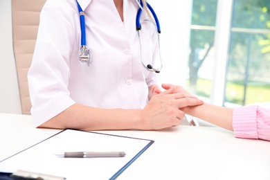 Doctor checking little girl's pulse in hospital