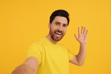 Photo of Smiling man taking selfie on yellow background