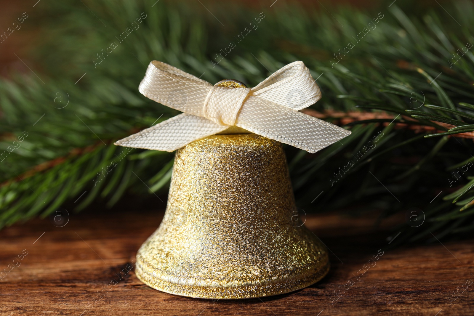 Photo of Bell and fir tree branches on wooden table, closeup. Christmas decor