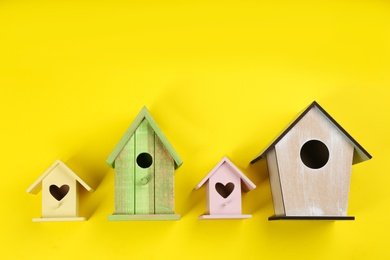 Photo of Collection of handmade bird houses on yellow background, flat lay