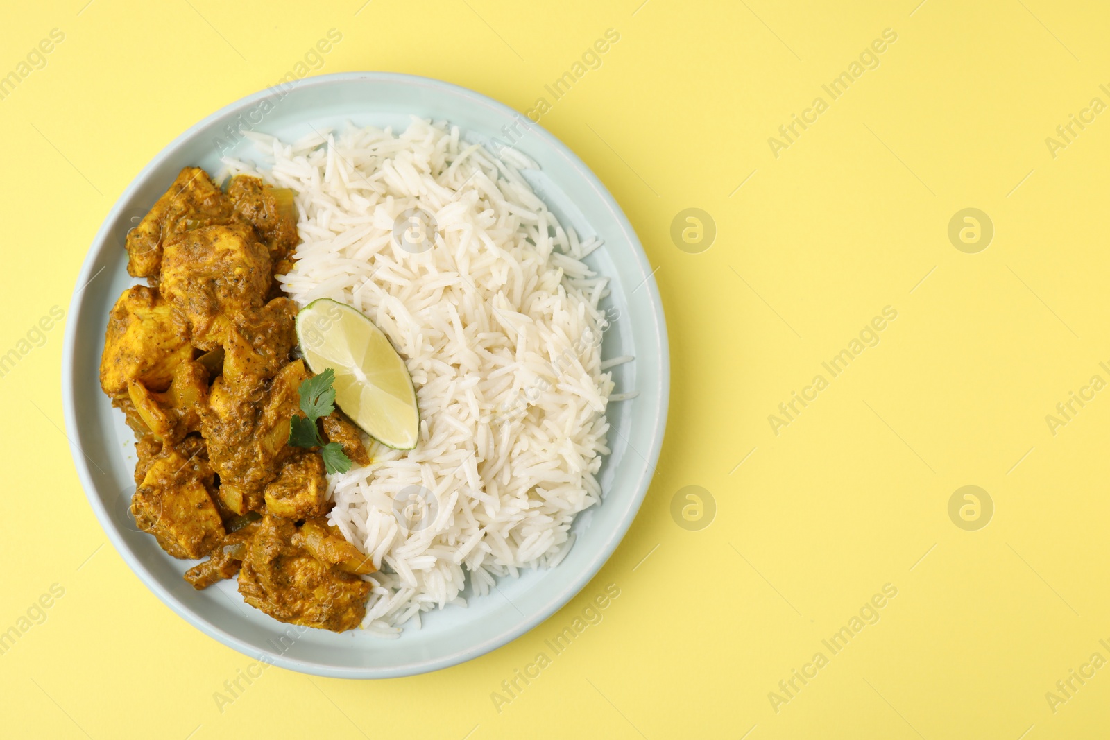 Photo of Delicious chicken curry with rice on yellow background, top view. Space for text