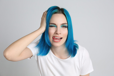 Photo of Young woman with bright dyed hair on light grey background