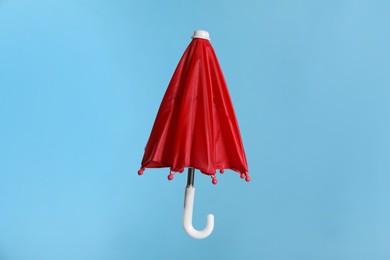 Photo of Closed small red umbrella on light blue background