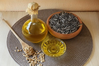Photo of Organic sunflower oil and seeds on white wooden table
