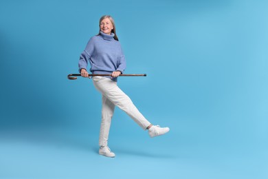 Photo of Senior woman with walking cane on light blue background