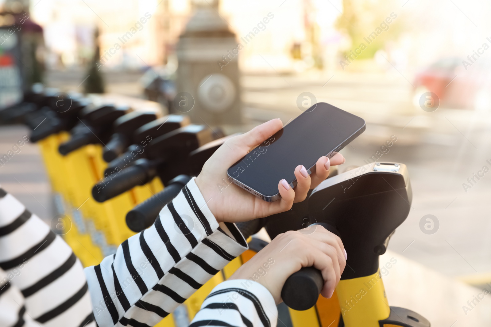 Photo of Woman using smartphone to pay and unblock electric kick scooter outdoors, closeup