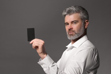 Photo of Handsome man holding blank business card on grey background