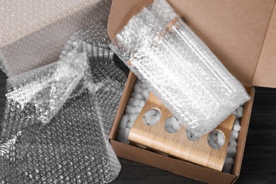 Test tubes in cardboard box and bubble wrap on dark wooden table