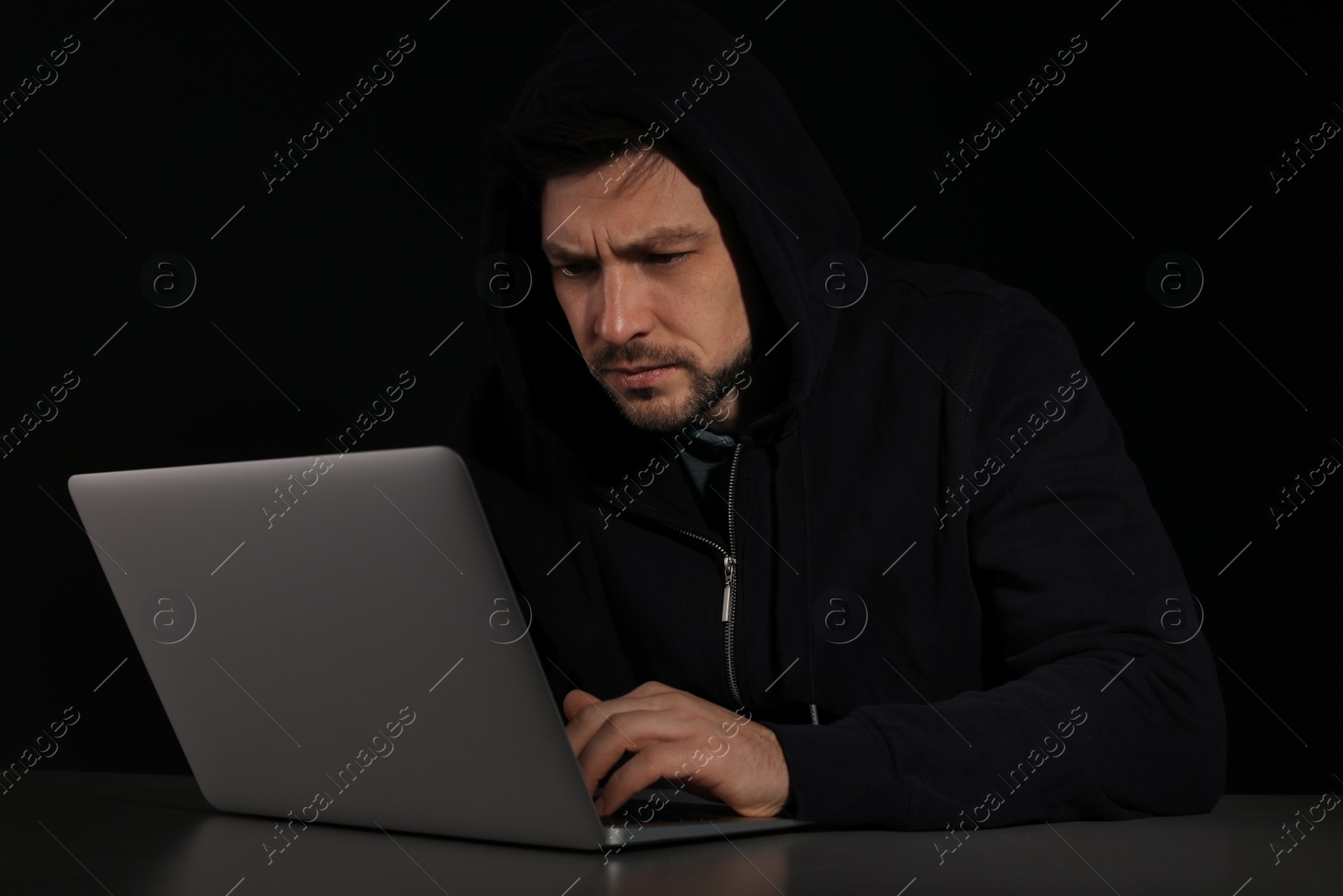 Photo of Man using laptop in darkness. Criminal activity