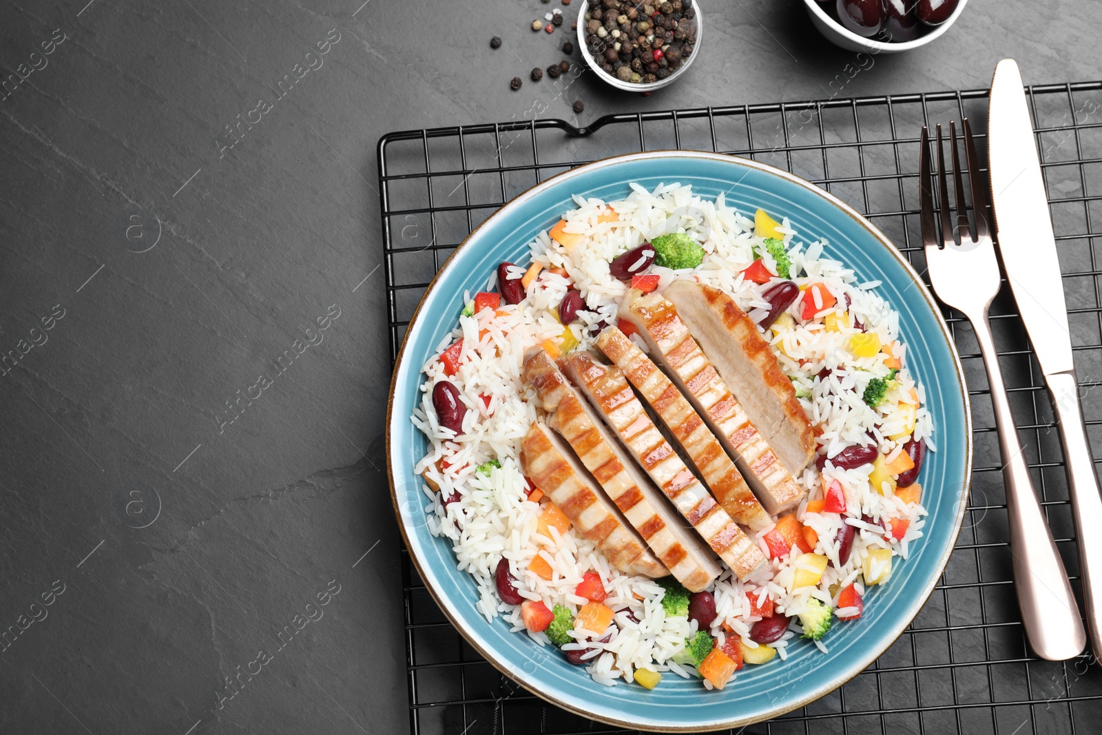 Photo of Tasty rice with beans and meat served on black table, flat lay