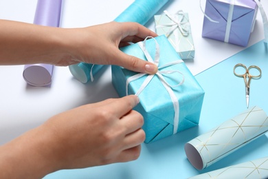 Woman decorating gift box on color background, closeup