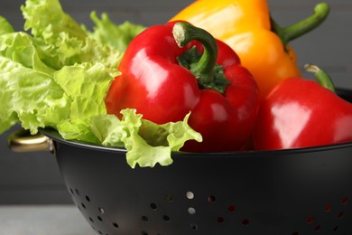 Photo of Vegetables in black colander on blurred background, closeup