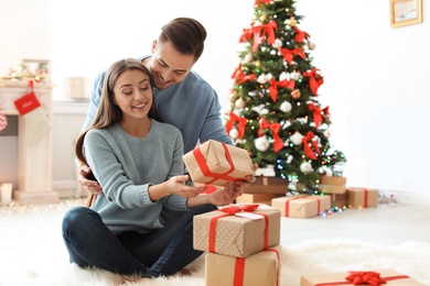 Young man giving Christmas gift to his girlfriend at home
