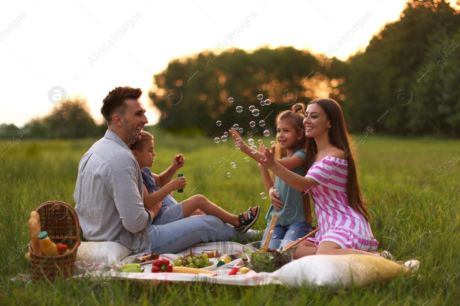 Photo of Happy family having picnic in park at sunset