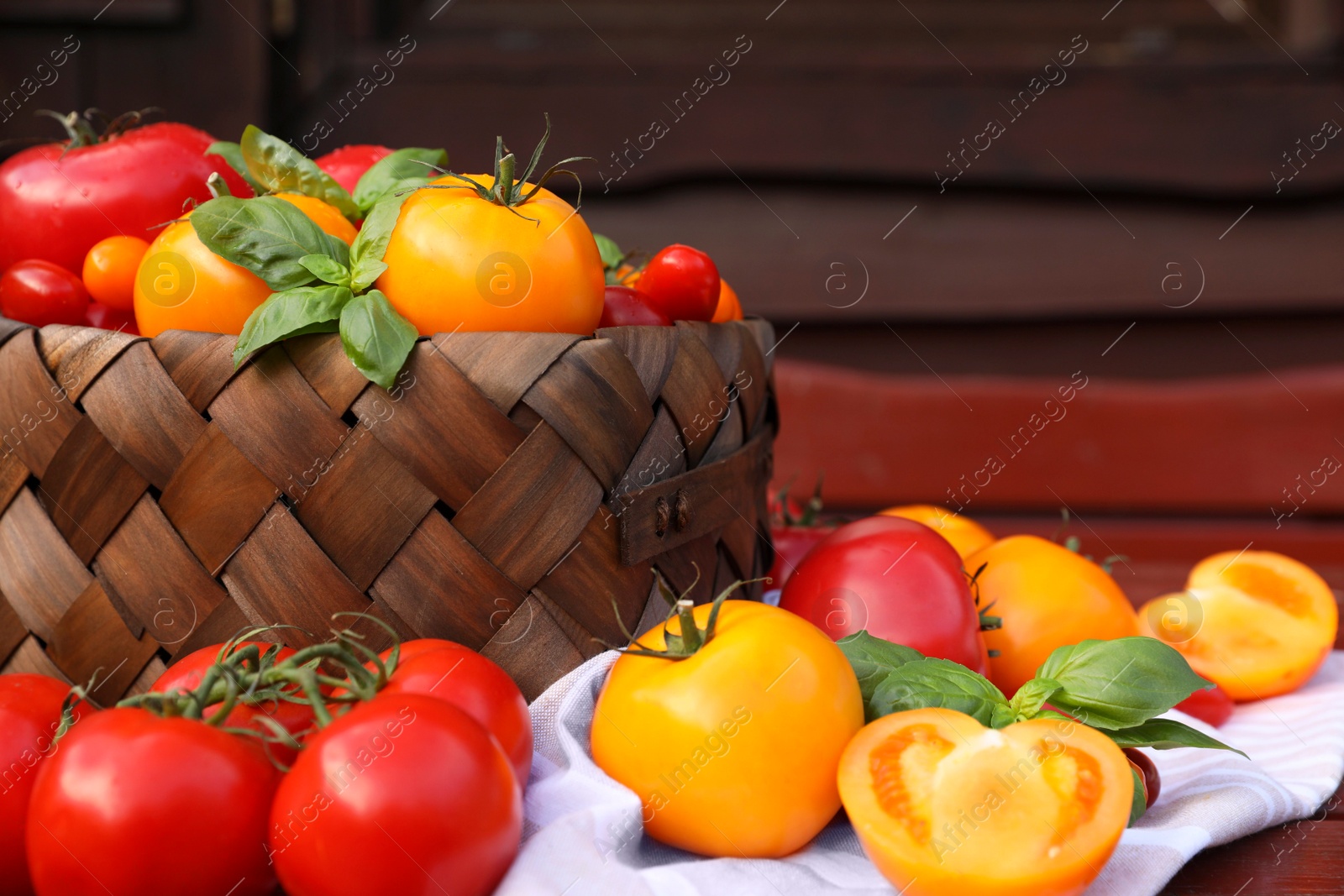 Photo of Different sorts of tomatoes with basil on wooden table