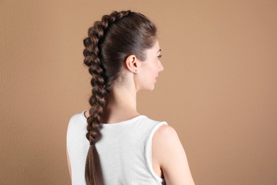 Photo of Woman with braided hair on light brown background