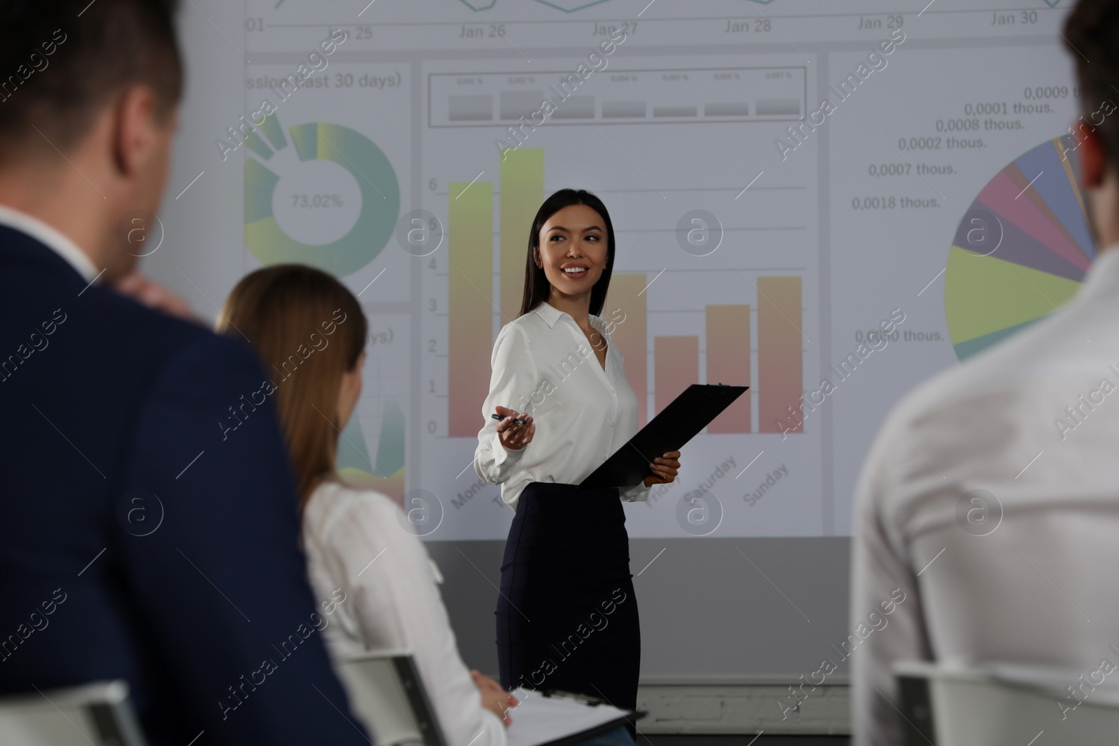 Photo of Female business trainer giving lecture in conference room with projection screen