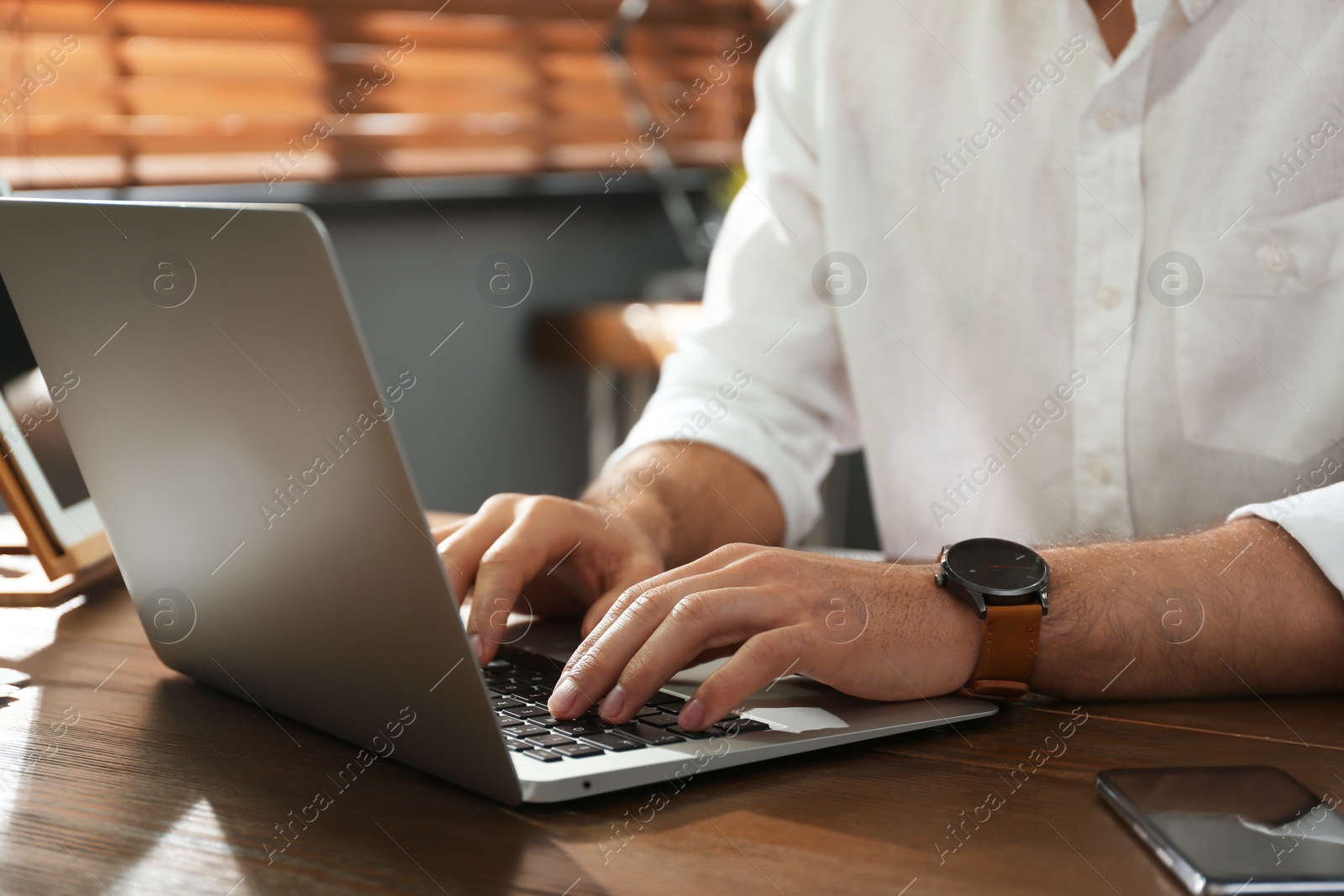 Photo of Freelancer working on laptop at table indoors, closeup