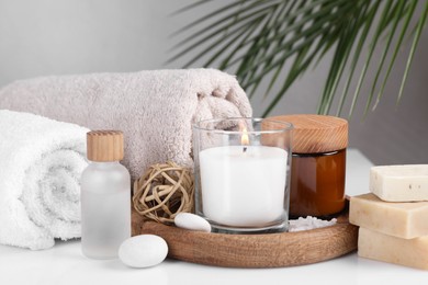 Composition with spa supplies on white table and palm leaf