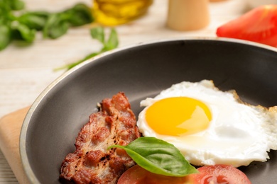 Pan with fried sunny side up egg and bacon on table, closeup